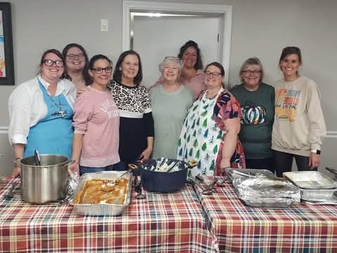 Group of women posing in front of food they cooked for the church Thanksgiving meal